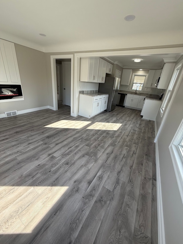 unfurnished living room with visible vents, dark wood-type flooring, and baseboards