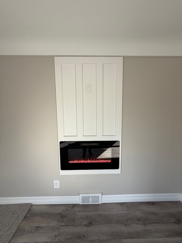 details with a glass covered fireplace, visible vents, baseboards, and wood finished floors