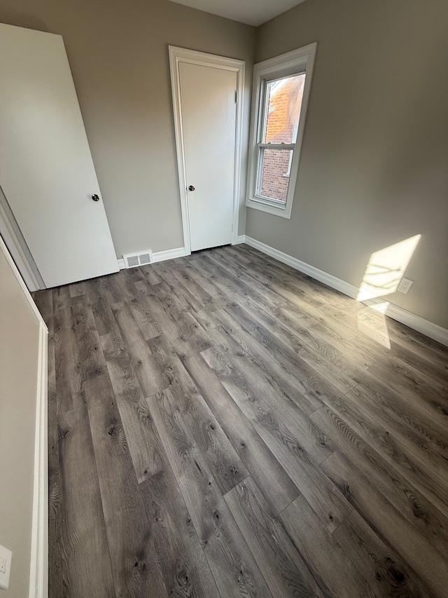 unfurnished bedroom with visible vents, baseboards, and wood finished floors