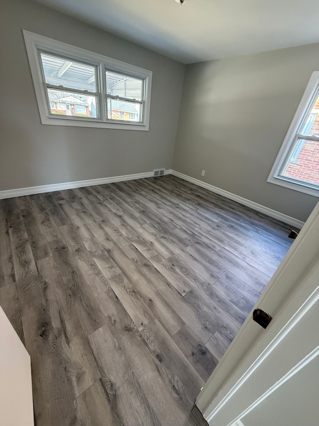 spare room featuring visible vents, baseboards, and wood finished floors