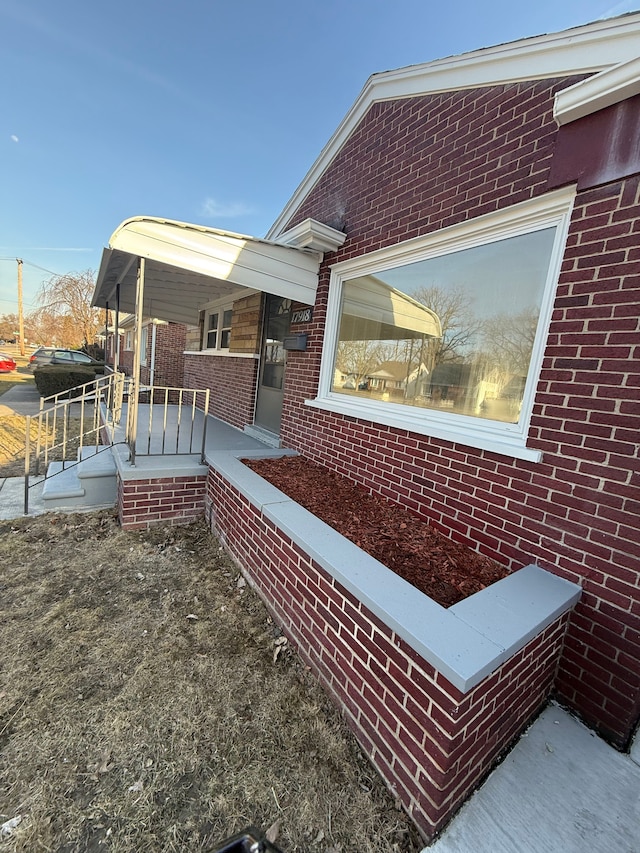 view of side of home with brick siding and covered porch