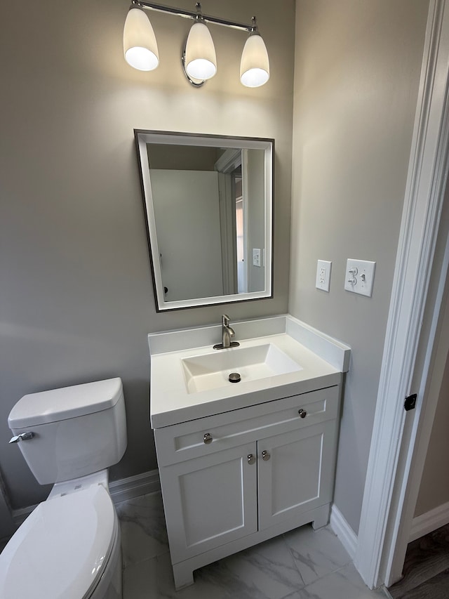 bathroom with marble finish floor, toilet, vanity, and baseboards