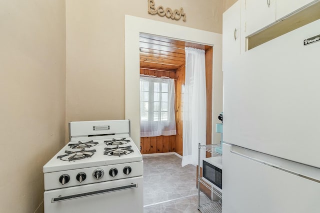 kitchen with white appliances, white cabinetry, wooden ceiling, and baseboards