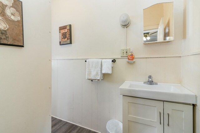 bathroom with wainscoting, wood finished floors, and vanity