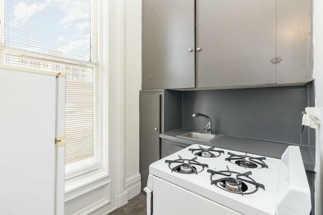 kitchen with a sink, white appliances, and dark wood-style flooring