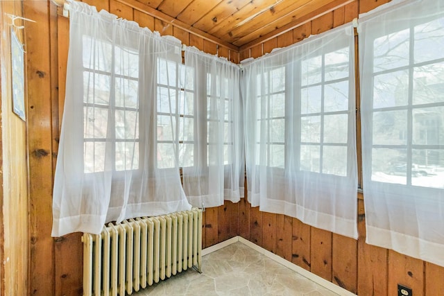 sunroom / solarium featuring plenty of natural light, wooden ceiling, and radiator heating unit