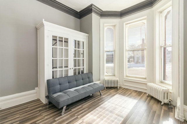 sitting room featuring radiator, wood finished floors, baseboards, and ornamental molding