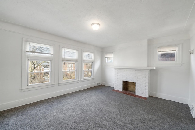 unfurnished living room with visible vents, baseboards, carpet flooring, a fireplace, and a textured ceiling