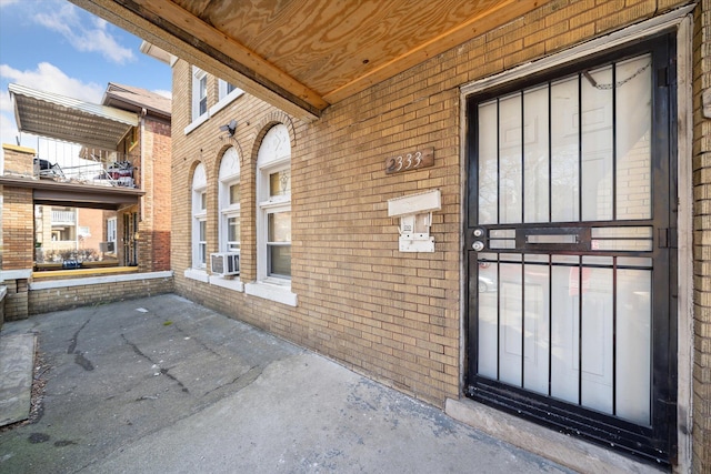 view of exterior entry featuring brick siding and cooling unit