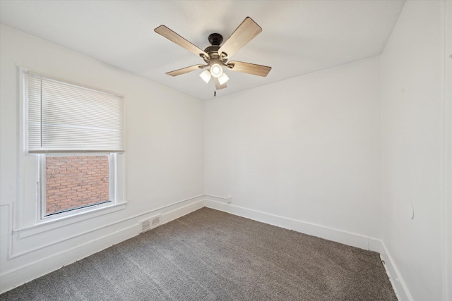 spare room featuring visible vents, baseboards, ceiling fan, and dark carpet