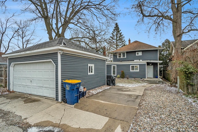 exterior space featuring a garage, an outdoor structure, a chimney, and fence