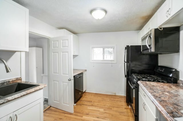 kitchen featuring light wood finished floors, white cabinetry, black appliances, and a sink