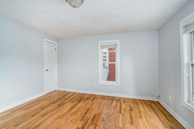 unfurnished room featuring plenty of natural light, baseboards, and wood finished floors