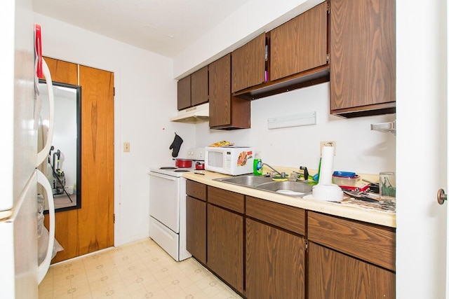 kitchen with white appliances, light floors, a sink, light countertops, and under cabinet range hood