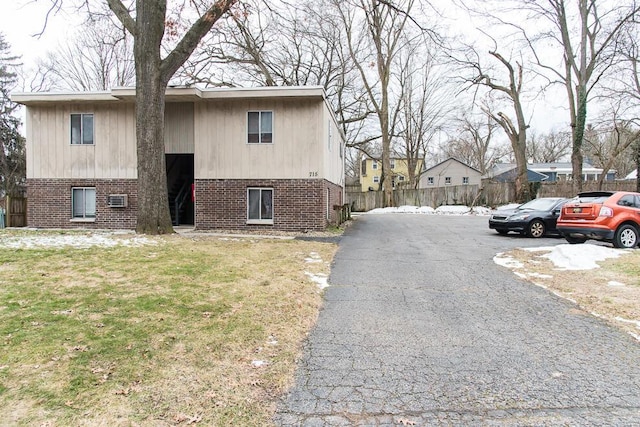 view of property exterior with fence, brick siding, and a lawn