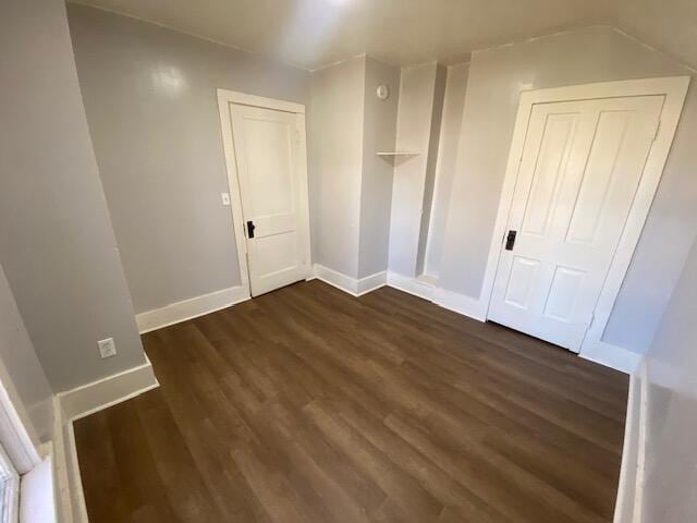 additional living space featuring dark wood finished floors and baseboards