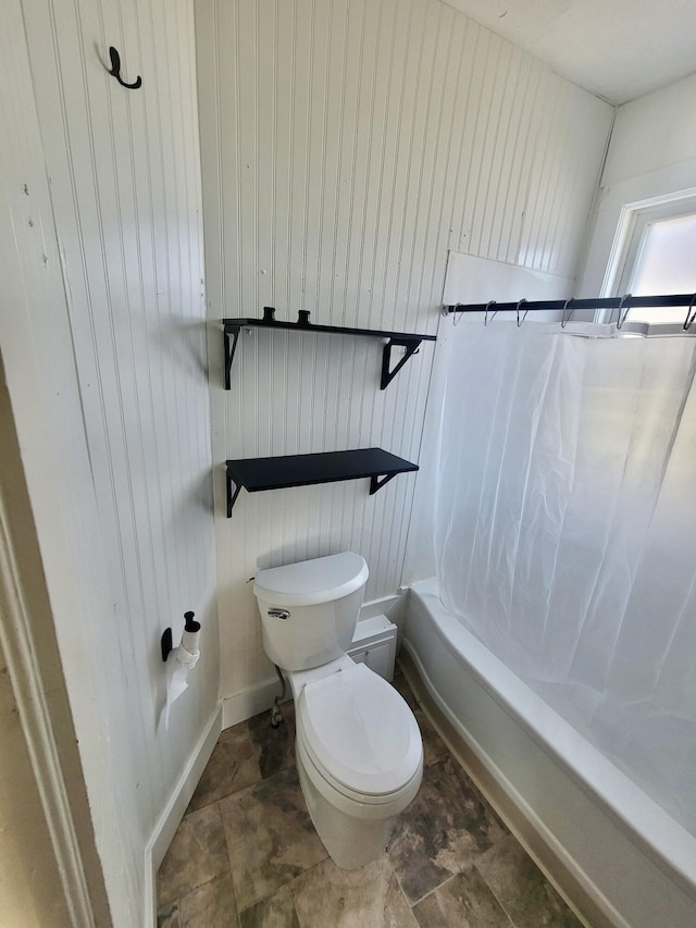 full bathroom featuring toilet, shower / tub combo with curtain, and stone finish flooring