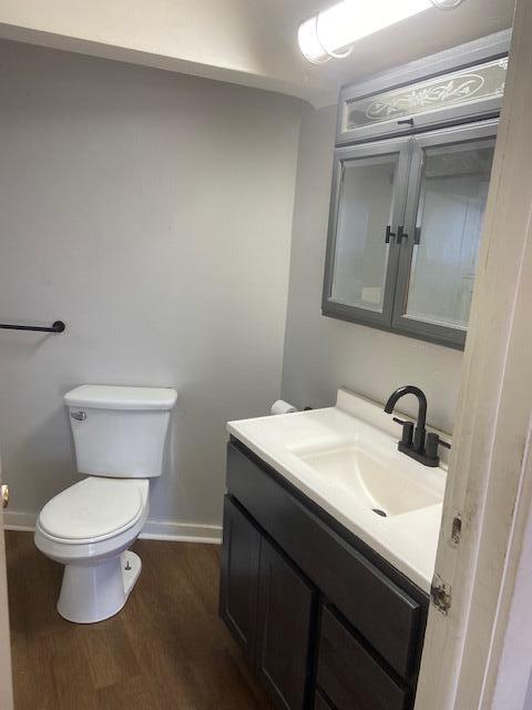 bathroom featuring vanity, toilet, wood finished floors, and baseboards