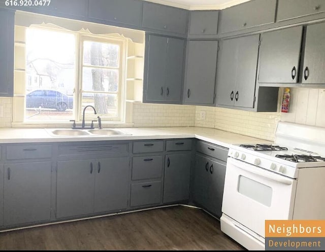 kitchen with dark wood-style floors, white range with gas cooktop, gray cabinetry, a sink, and backsplash