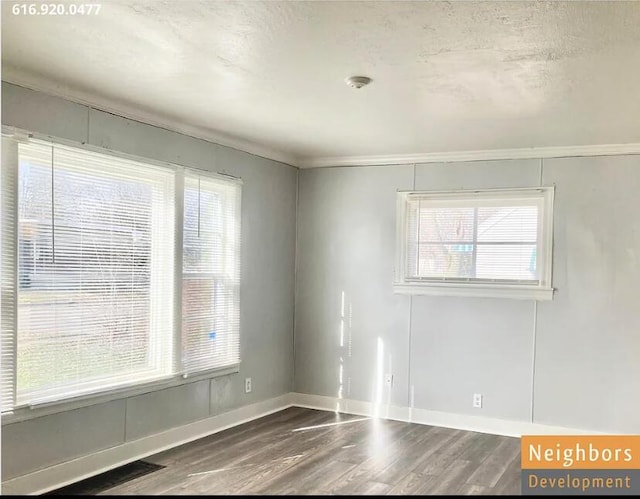 unfurnished room with baseboards, plenty of natural light, a textured ceiling, and wood finished floors