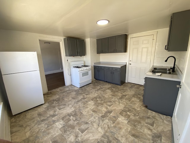 kitchen featuring gray cabinets, a sink, white appliances, light countertops, and decorative backsplash