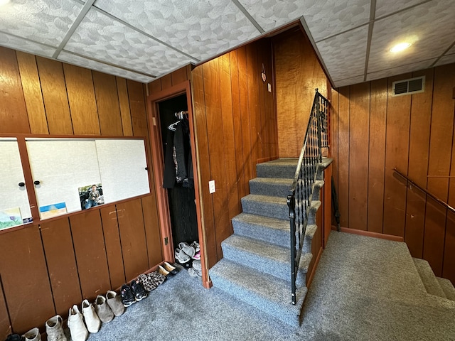 stairs featuring visible vents, carpet floors, and wood walls