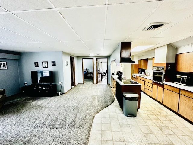 kitchen featuring visible vents, oven, light countertops, a paneled ceiling, and light colored carpet