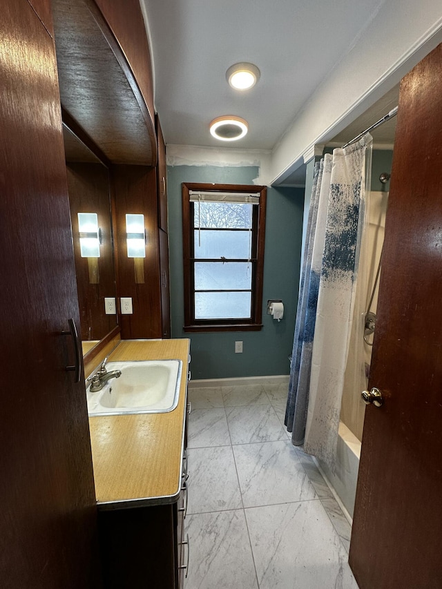 full bath with marble finish floor, wooden walls, shower / tub combo, baseboards, and vanity