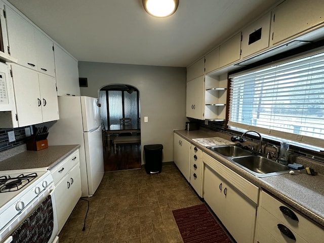 kitchen featuring a sink, decorative backsplash, arched walkways, white cabinetry, and open shelves