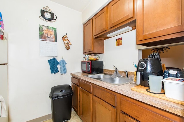 kitchen with a sink, brown cabinetry, and light countertops