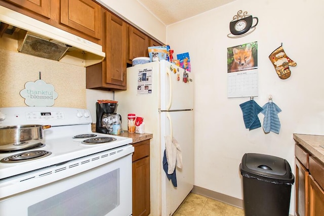 kitchen featuring white appliances, brown cabinetry, baseboards, and under cabinet range hood