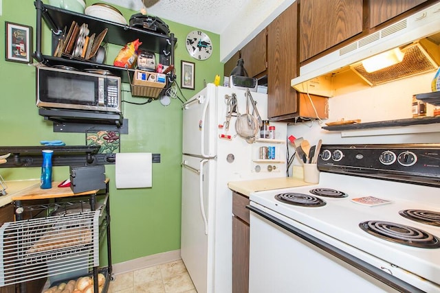 kitchen with stainless steel microwave, under cabinet range hood, light countertops, electric range, and a textured ceiling