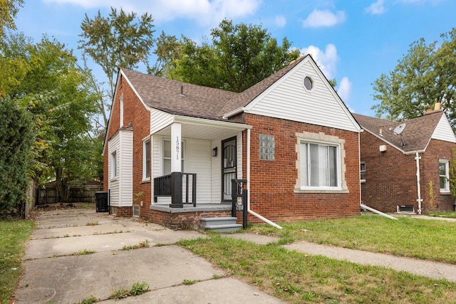 bungalow-style house with a front yard, brick siding, and a shingled roof