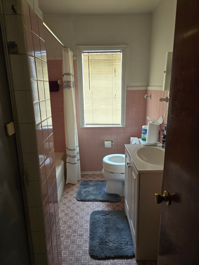 bathroom featuring toilet, vanity, shower / bath combo, tile patterned floors, and tile walls