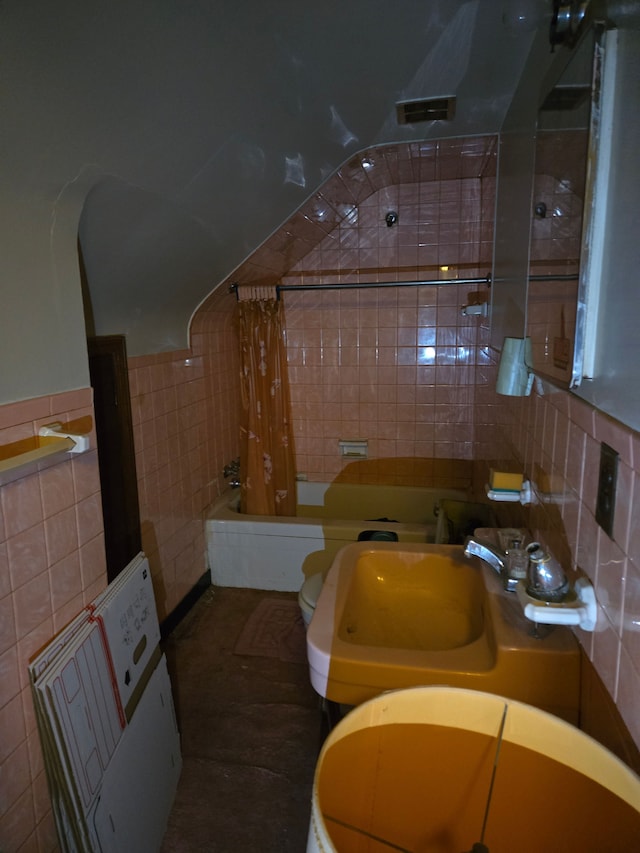 bathroom with tile walls, shower / tub combo, toilet, and a sink