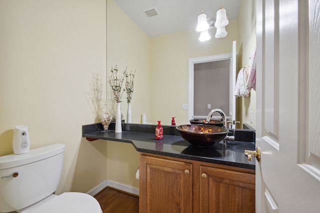 bathroom featuring vanity, wood finished floors, visible vents, baseboards, and toilet