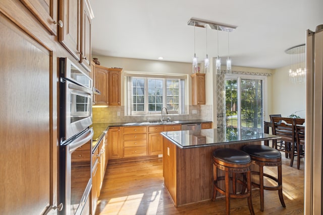 kitchen with light wood-style flooring, tasteful backsplash, a kitchen island, and stainless steel appliances