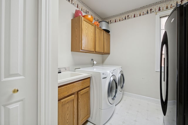 clothes washing area featuring a sink, cabinet space, baseboards, light floors, and washing machine and clothes dryer