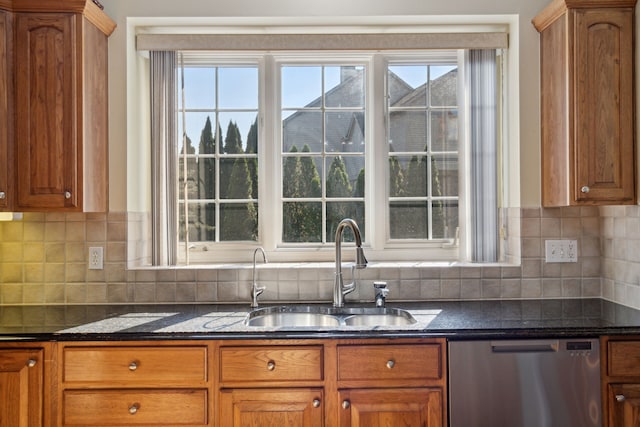 kitchen with a sink, dark stone counters, brown cabinets, and stainless steel dishwasher