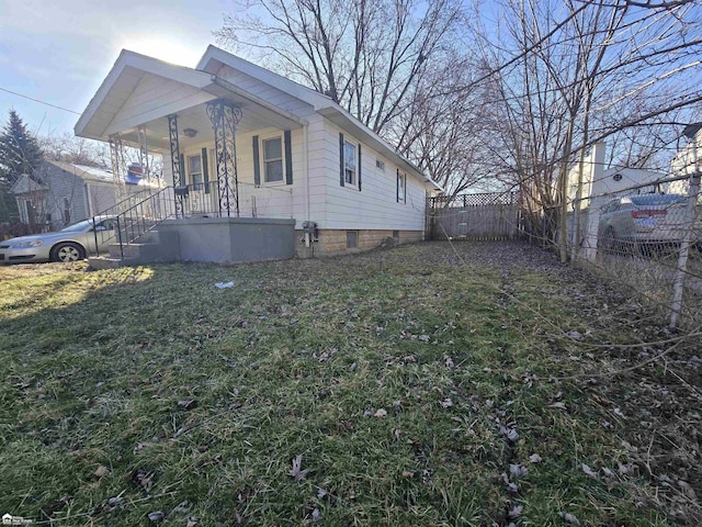 view of home's exterior featuring covered porch, a yard, and fence