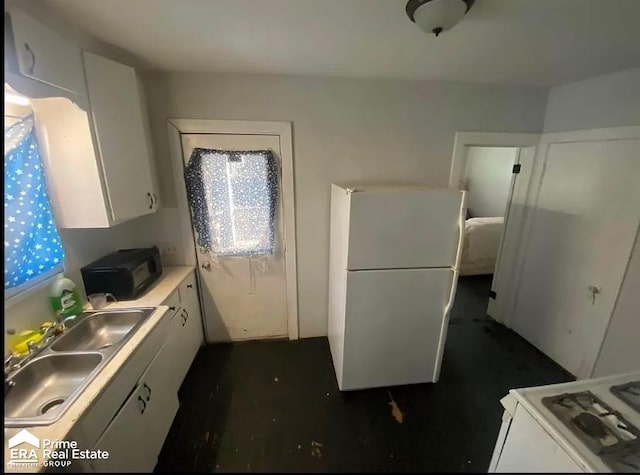 kitchen featuring a sink, freestanding refrigerator, white cabinets, black microwave, and light countertops