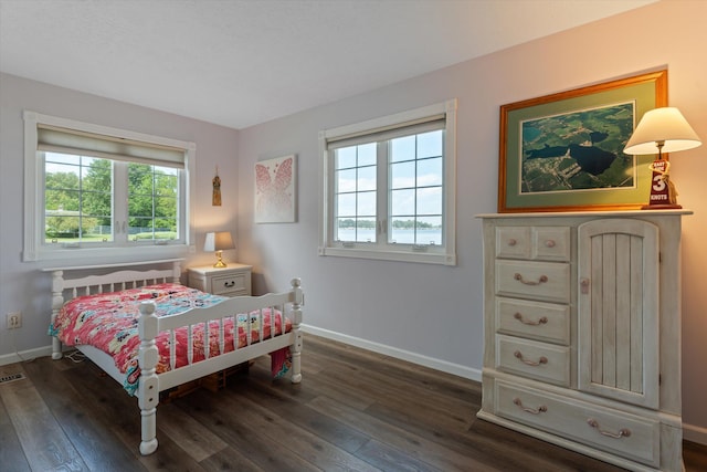 bedroom with visible vents, baseboards, and dark wood finished floors