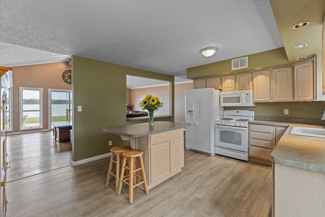 kitchen featuring white appliances, a kitchen island, a breakfast bar, and light wood finished floors