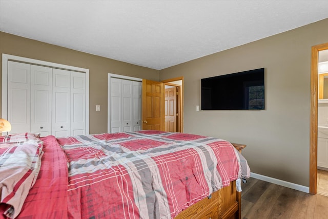 bedroom with wood finished floors, multiple closets, ensuite bathroom, and baseboards