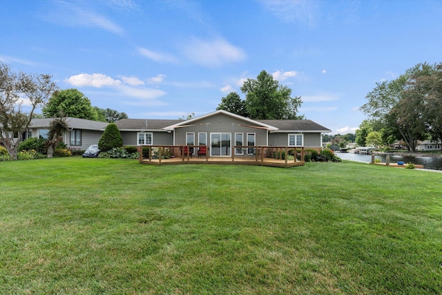 back of property with a lawn and a deck with water view