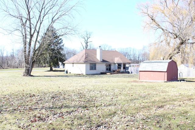 exterior space featuring a lawn, a chimney, a storage shed, and an outdoor structure