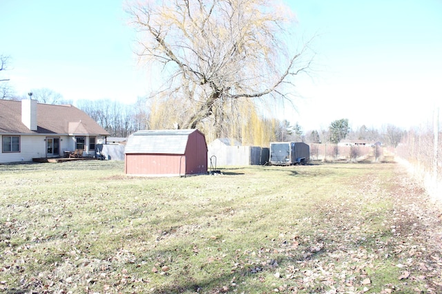 view of yard featuring a storage shed, fence, and an outdoor structure