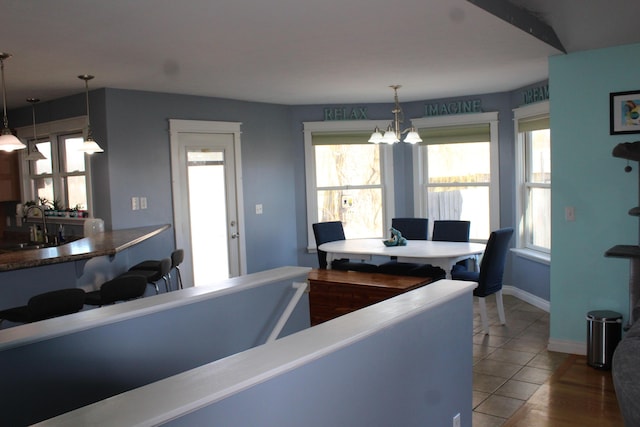 tiled dining room featuring an inviting chandelier, baseboards, and a sink