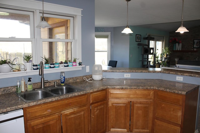 kitchen featuring brown cabinetry, decorative light fixtures, dishwasher, and a sink