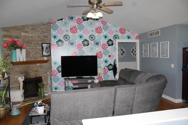 living room with visible vents, ceiling fan, vaulted ceiling, a fireplace, and wood finished floors